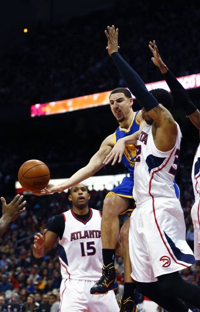 Klay Thompson drives between Hawks Mike Scott and Al Horford, left, Friday night. (Associated Press)