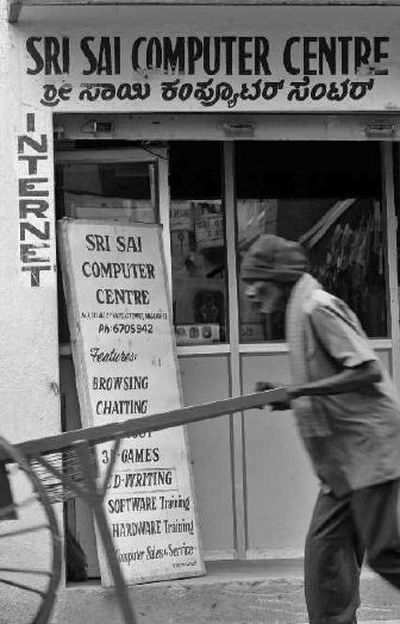 
People walk past a sign for an internet shop in Bangalore, India, earlier this month. Had the Internet been invented in China, you'd need some fluency in Chinese to type Web addresses. But as a U.S. invention, the Internet's lingua franca is English. 
 (Associated Press / The Spokesman-Review)