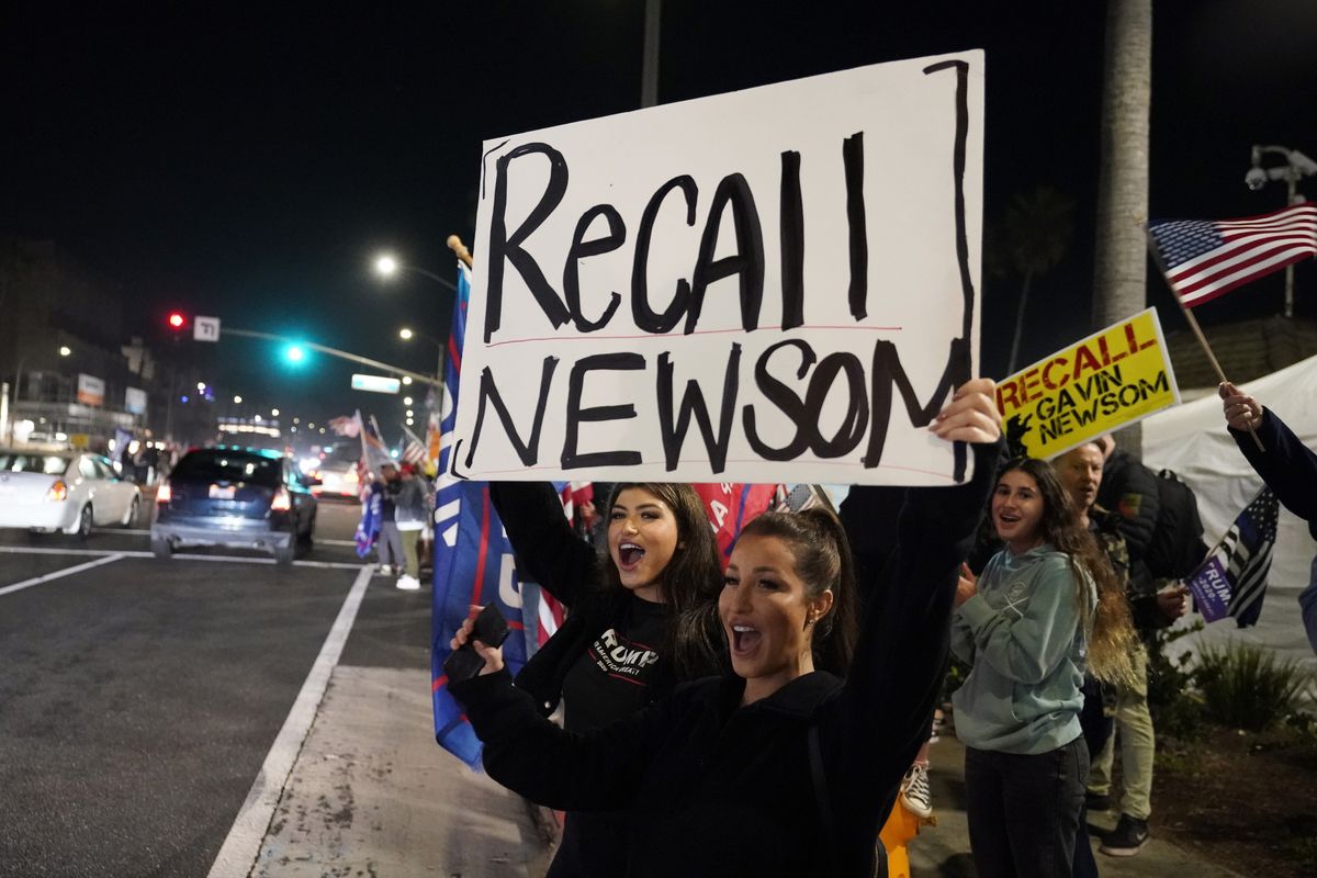 FILE - In this Nov. 21, 2020, file photo, demonstrators shout slogans while carrying a sign calling for a recall on Gov. Gavin Newsom during a protest against a stay-at-home order amid the COVID-19 pandemic in Huntington Beach, Calif. Organizers of the recall effort against Gov. Newsom collected enough valid signatures to qualify for the ballot. The California secretary of state’s office announced Monday, April 26, 2021 that more than 1.6 million signatures had been verified, about 100,000 more than needed to force a vote on the first-term Democrat.  (Marcio Jose Sanchez)