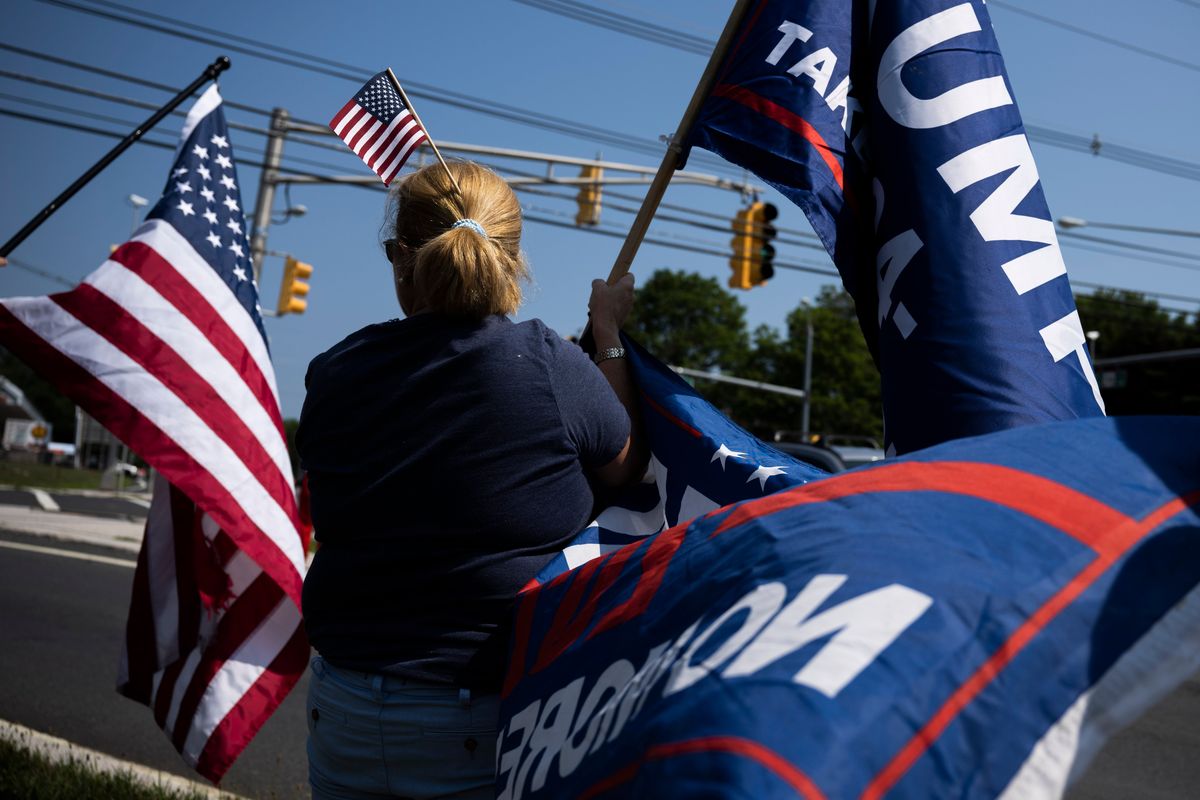 Lisa Burke of New Vernon, N.J., displays flags in support of former president Donald Trump near Trump National Golf Club on Sunday in Bedminster, N.J.   (Joe Lamberti/For the Washington Post)