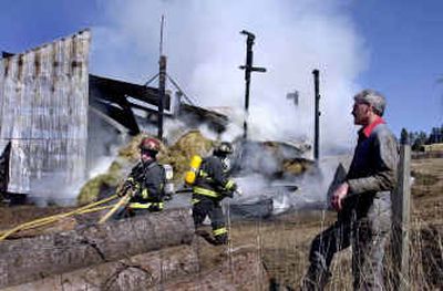 
Northern Lakes firefighters battle a fire  at a barn owned by John Matheson on Monday near Hauser Lake. Neighbor John Mobbs, right, showed up to help. 
 (Kathy Plonka / The Spokesman-Review)