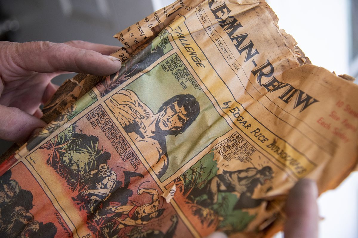 Dan Coyle, a landlord who is refurbishing a small rental house in the Gonzaga University neighborhood, reads a WWII-era color Tarzan comic in a newspaper he pulled off of water and sewer pipes, where they were presumably used as pipe insulation. He was replacing aging pipes Wednesday, May 26, 2021 in the old house which is rented out to Gonzaga University students who are out of the house for the short period between graduation and the start of the summer session.  (Jesse Tinsley/The Spokesman-Review)