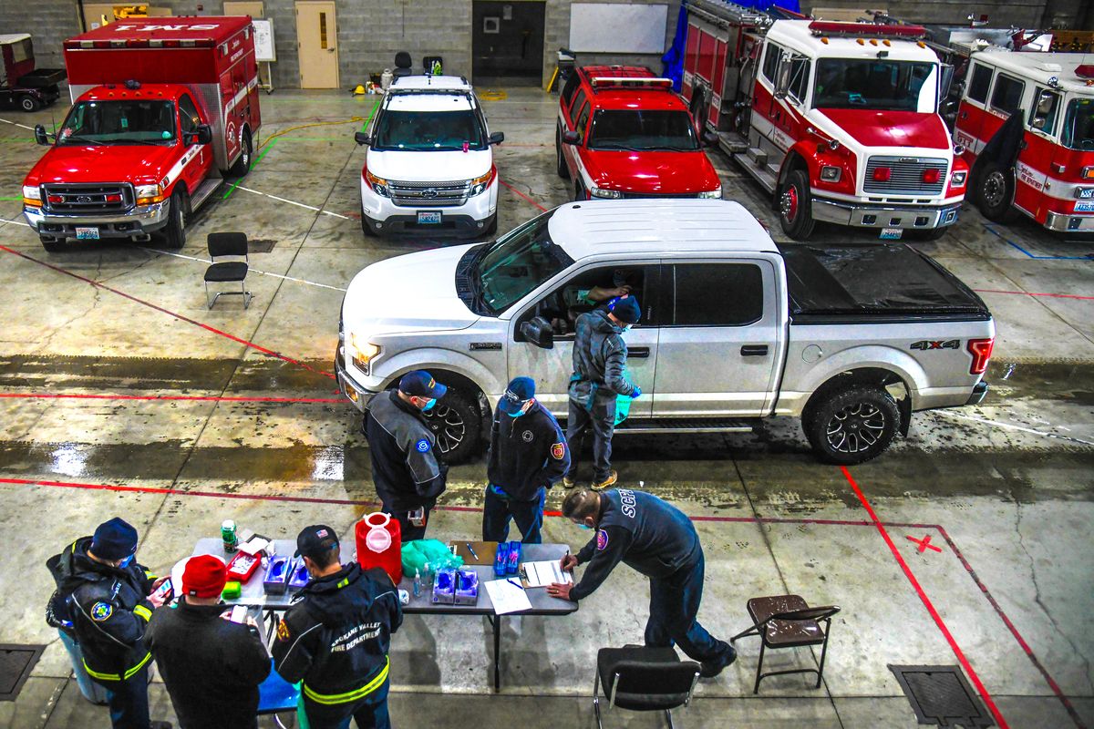 Paramedics administer a shot to a pickup driver, Monday, Jan. 4, 2021, at the Spokane Fire Training Center Field House. Local firefighters and first responders started getting their COVID-19 vaccines Monday at a drive through vaccination clinic put on by the Spokane Regional Health District.  (DAN PELLE/THE SPOKESMAN-REVIEW)