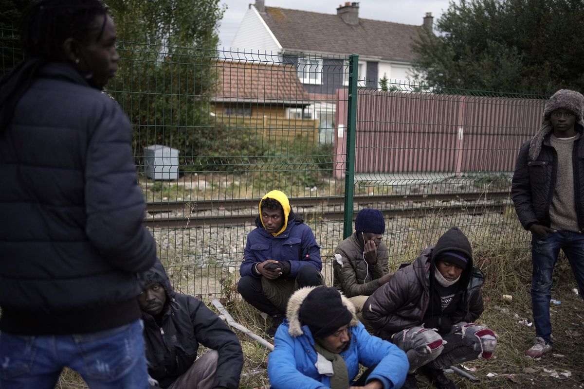 Migrants wait for food distribution at a camp in Calais, northern France, Thursday, Oct. 14, 2021. The price to cross the English Channel varies according to the network of smugglers, between 3,000 and 7,000 euros. Often, the fee also includes a very short-term tent rental in the windy dunes of northern France and food cooked over fires that sputter in the rain that falls for more than half the month of November in the Calais region.  (Christophe Ena)