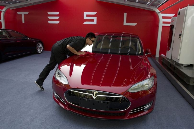 In this 2014 photo, a worker cleans a Tesla Model S sedan before a event to deliver the first set of cars to customers in Beijing. (AP Photo/Ng Han Guan)