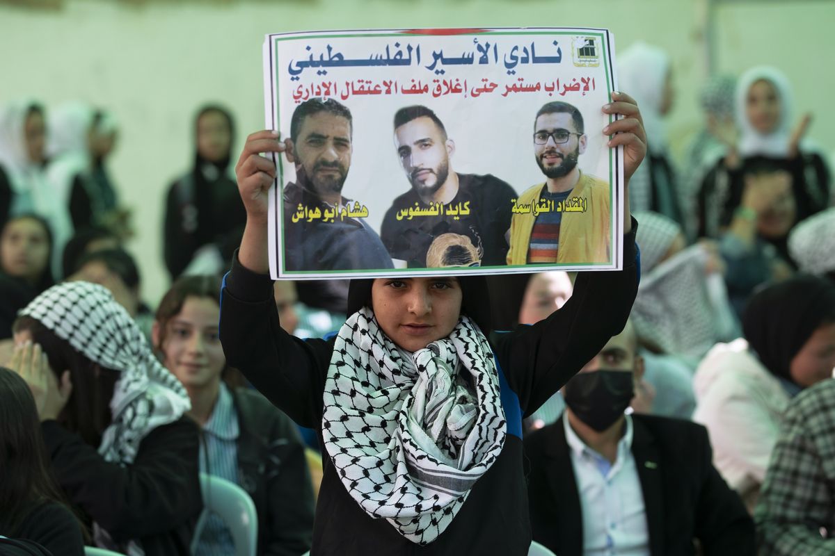 Protesters carry posters showing Kayed Fasfous, a Palestinian prisoner who has been on hunger strike for 120 days to protest being detained without charge by Israel, in the village of ad-Dhahiriya, near the West Bank town of Hebron, Thursday, Nov. 11, 2021. Israel faced growing calls on Thursday to release five Palestinians who have been on hunger strike for weeks to protest a controversial policy of holding them indefinitely without charge. Arabic on poster reads "Freedom for prisoners who are on hunger strike".  (Majdi Mohammed)