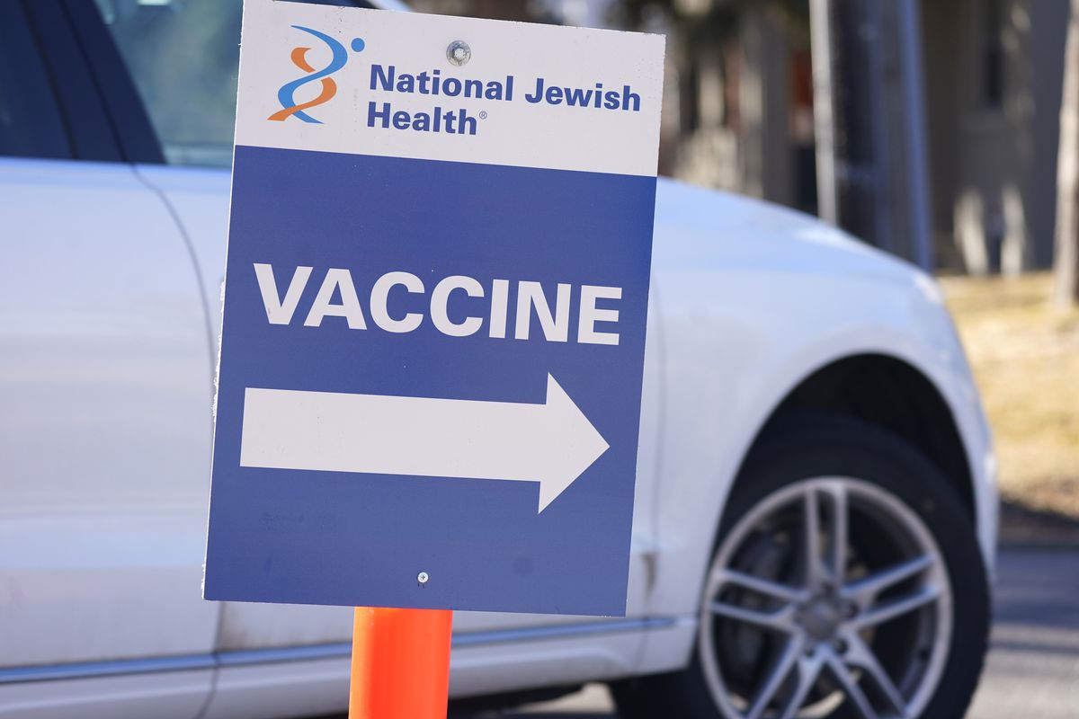 A sign directs motorist to a vaccination site at National Jewish Hospital on March 6, 2021, in east Denver. Merriam-Webster has declared vaccine its 2021 word of the year.  (David Zalubowski)