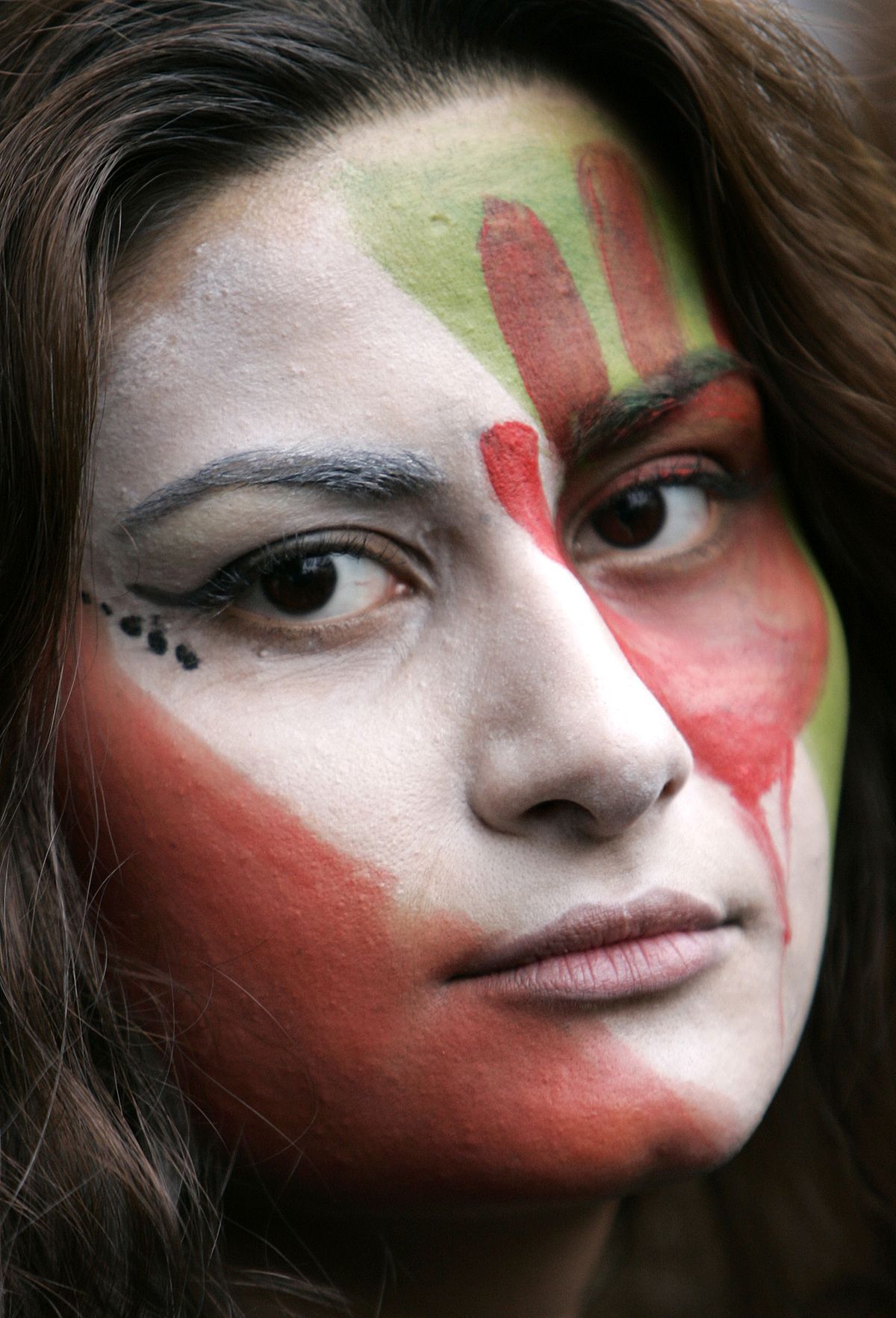 A protester’s face is painted in the colors of the Iranian flag with a blooded hand, outside the Iranian Embassy in London on Thursday. (Akira Suemori / The Spokesman-Review)