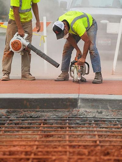 Russ Grant, with the City of Coeur d’Alene Streets Department, uses a concrete saw to cut a section of roadway near the intersection of Fourth Street and Montana Avenue during construction on Monday. (Shawn Gust / Coeur d'Alene Press)