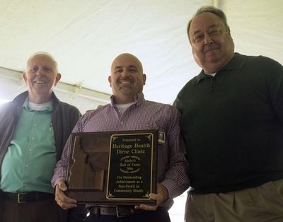 Heritage Health CEO Mike Baker, center, holds a plaque commemorating the clinic's induction into the Idaho Hall of Fame as he’s flanked by Idaho Hall of Fame board members Tony Stewart, left, and Freeman Duncan. (LOREN BENOIT/CDA PRESS)