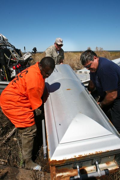 Joe Johnson, corrections officer Sgt. David Conner  and an inmate from the Phelps Correctional Center load a coffin onto an airboat in the North Big Lake area of Cameron Parish, La., on  Oct. 8.  (Associated Press / The Spokesman-Review)