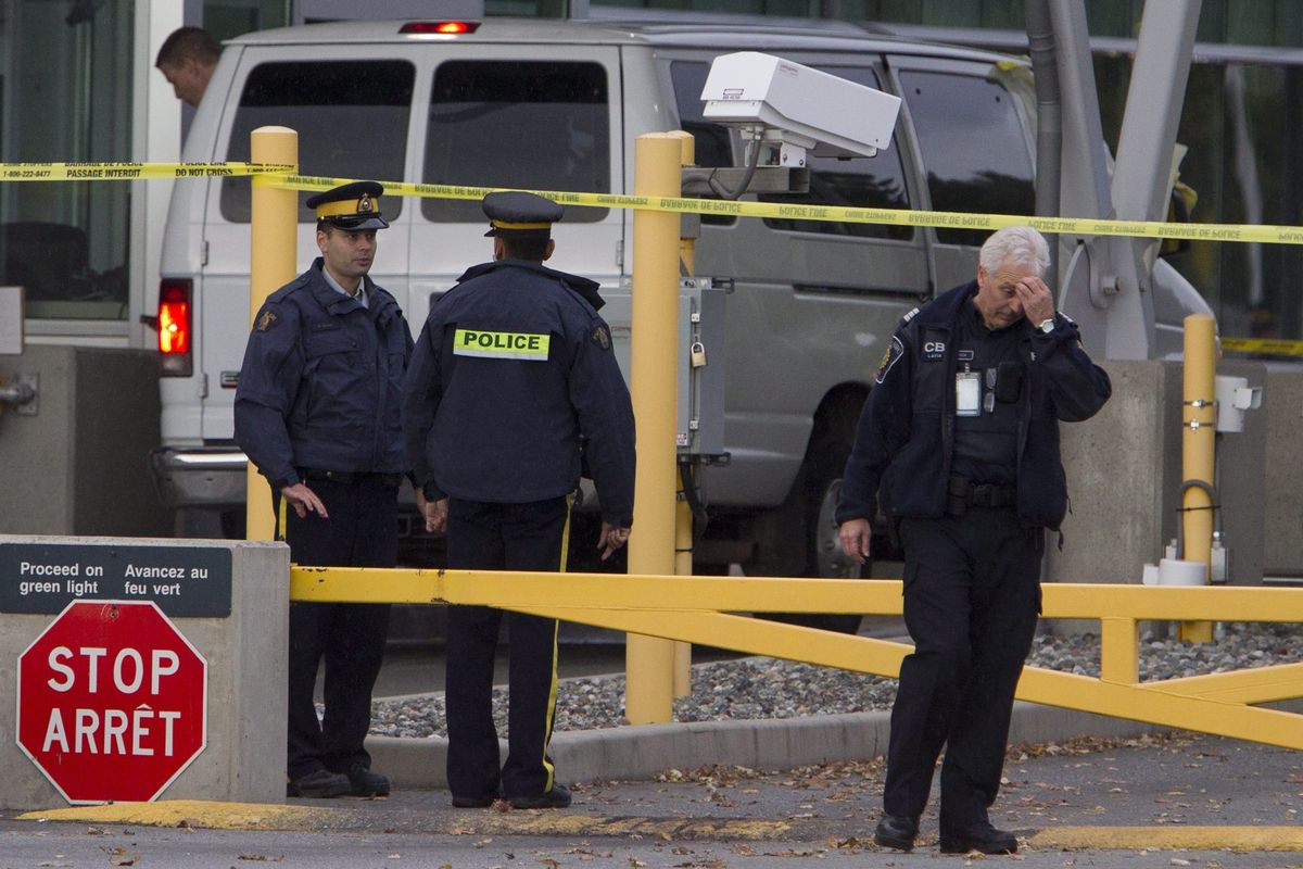 Police investigate a van at the scene of a shooting at the Blaine, Wash./Surrey, British Columbia border crossing Tuesday, Oct. 16, 2012. Royal Canadian Mounted Police Cpl. Bert Paquet says a border officer was in her booth when she was shot in the neck at about 2 p.m. Tuesday by a man trying to enter Canada in a van with Washington state plates. (Jonathan Hayward / The Canadian Press)