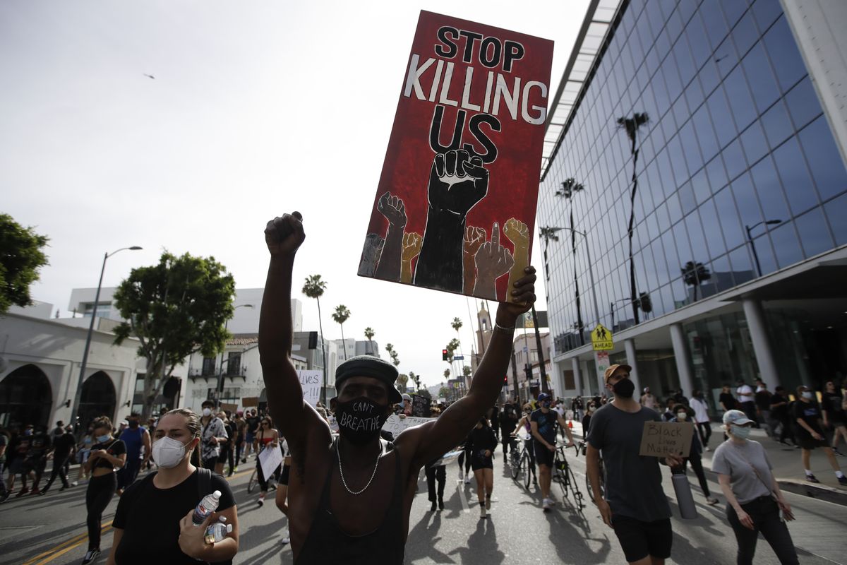 FILE - A protester carries a sign in the Hollywood area of Los Angeles on June 1, 2020, during demonstrations after the killing of George Floyd which sparked calls for a racial reckoning to address structural racism that has created longstanding inequities impacting generations of Black Americans. Floyd