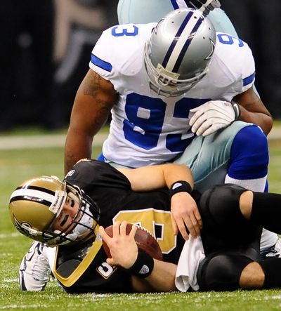 Dallas linebacker Anthony Spencer looms over New Orleans quarterback Drew Brees after a sack for a 10-yard loss Saturday.  (Associated Press)