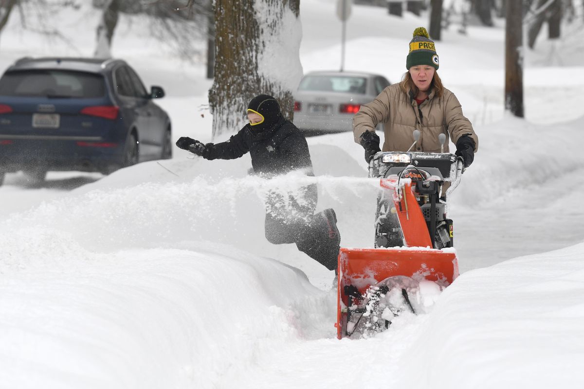 Amanda Roggenbauer runs a snowblower past several homes in her neighborhood while her son, Erik Roggenbauer, 8, dives into the snow bank for fun Mondayalong Rockwood Boulevard on the South Hill of Spokane. (Jesse Tinsley / The Spokesman-Review)