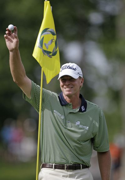 Steve Stricker is all smiles as he waves to the gallery following a hole-in-one on the eighth hole on the way to the lead. (Associated Press)