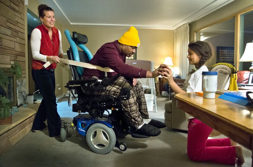 Al Palm works on his balance and strength, with the help of occupational therapist Emily Querna, left, and his daughter Joelle, on Dec. 2 at his home in northwest Spokane. (Dan Pelle)