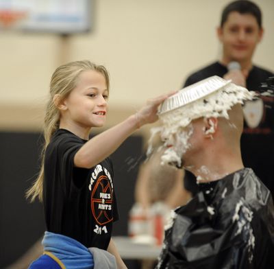 Just dessert: Akylah Beitey puts a third cream pie in the face of Orchard Center Elementary School teacher Brett Maloney on Friday. The students held an assembly for their monthly awards, and to celebrate a cancer fundraiser students had names drawn to pie the teacher and help shave the head of Principal Travis Peterson. (Christopher Anderson)