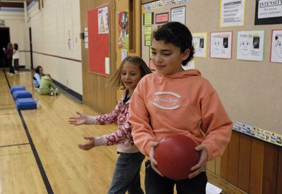 Otis Orchards Elementary School fourth-grader Britney Martin (in orange) and classmate Hannah Brake do medicine ball twisters during a health and fitness circuit training class at the school. Students are participating in a new Five for Life fitness curriculum as a result of a grant the East Valley School District was awarded.  (J. BART RAYNIAK / The Spokesman-Review)