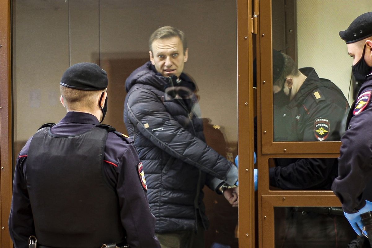 In this photo taken from a footage provided by the Babuskinsky District Court Tuesday, Feb. 16, 2021, Russian opposition leader Alexei Navalny, center, enters a cage to attend a hearing on his charges for defamation in the Babuskinsky District Court in Moscow, Russia. Navalny is accused of defaming a World War II veteran who was featured in a video last year advertising constitutional amendments that allowed an extension of President Vladimir Putin