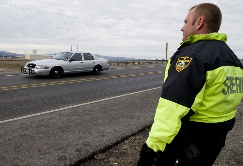 Sheriff’s Deputy Craig Chamberlin monitors how well a test car brakes after an  application of liquid de-icer near the intersection of  Wellesley and Trent avenues Jan. 29, during the reconstruction of an accident that  injured two East Valley High students Dec. 29.colinm@spokesman.com (Colin Mulvany)