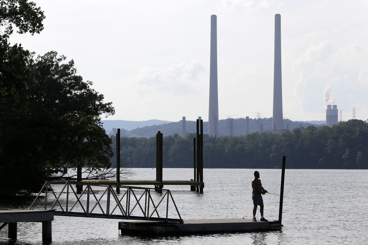 FILE - In this Aug. 7, 2019, file photo, a man fishes at William B. Ladd Park near the Kingston Fossil Plant in Kingston, Tenn. The largest public power company in the U.S. is launching a program to develop and fund new small modular nuclear reactors as part of its strategy to dramatically reduce greenhouse gas emissions. The board for the Tennessee Valley Authority on Thursday, Feb. 10, 2022 authorized the program to assess moving forward with new nuclear technology, with up to $200 million to be spent for the first phase. (Mark Humphrey)