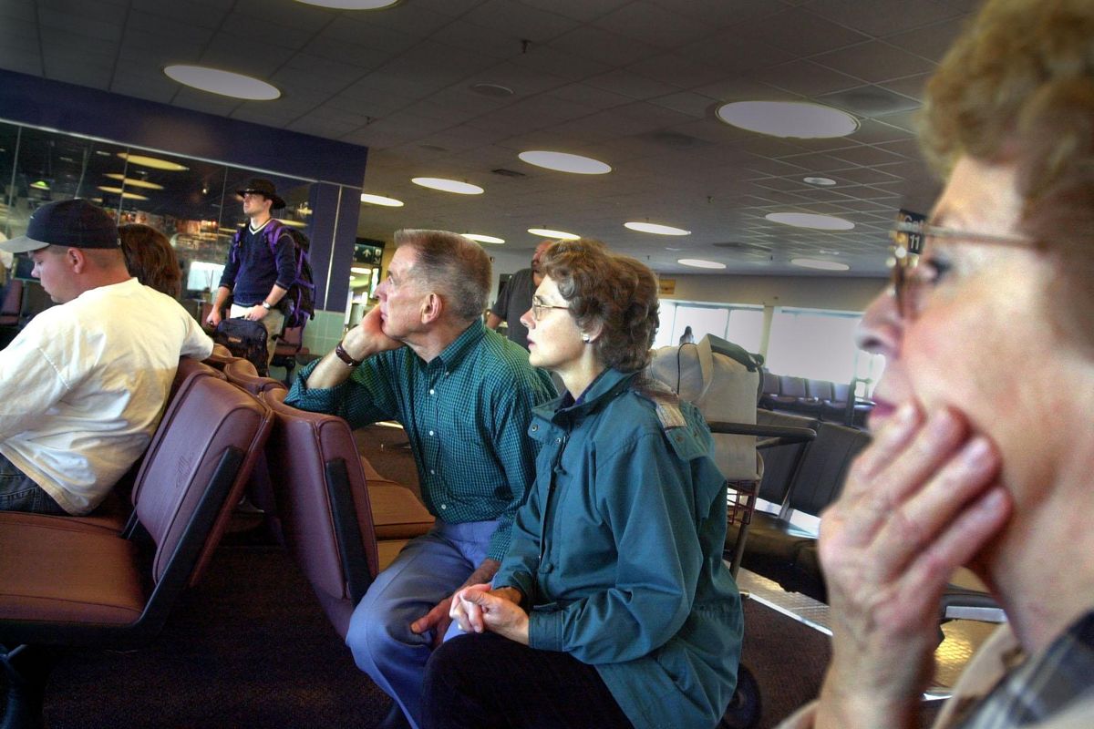 Joan Arnzen, right, puts her hand to her mouth as she sits with her brother Bob Guske, center in green, watch news reports of 9/11 attacks. They were trying to fly home from a weekend family reunion and were in the Spokane International Airport when the attacks occurred. All flights were cancelled and the airport closed. (Christopher Anderson / The Spokesman-Review)
