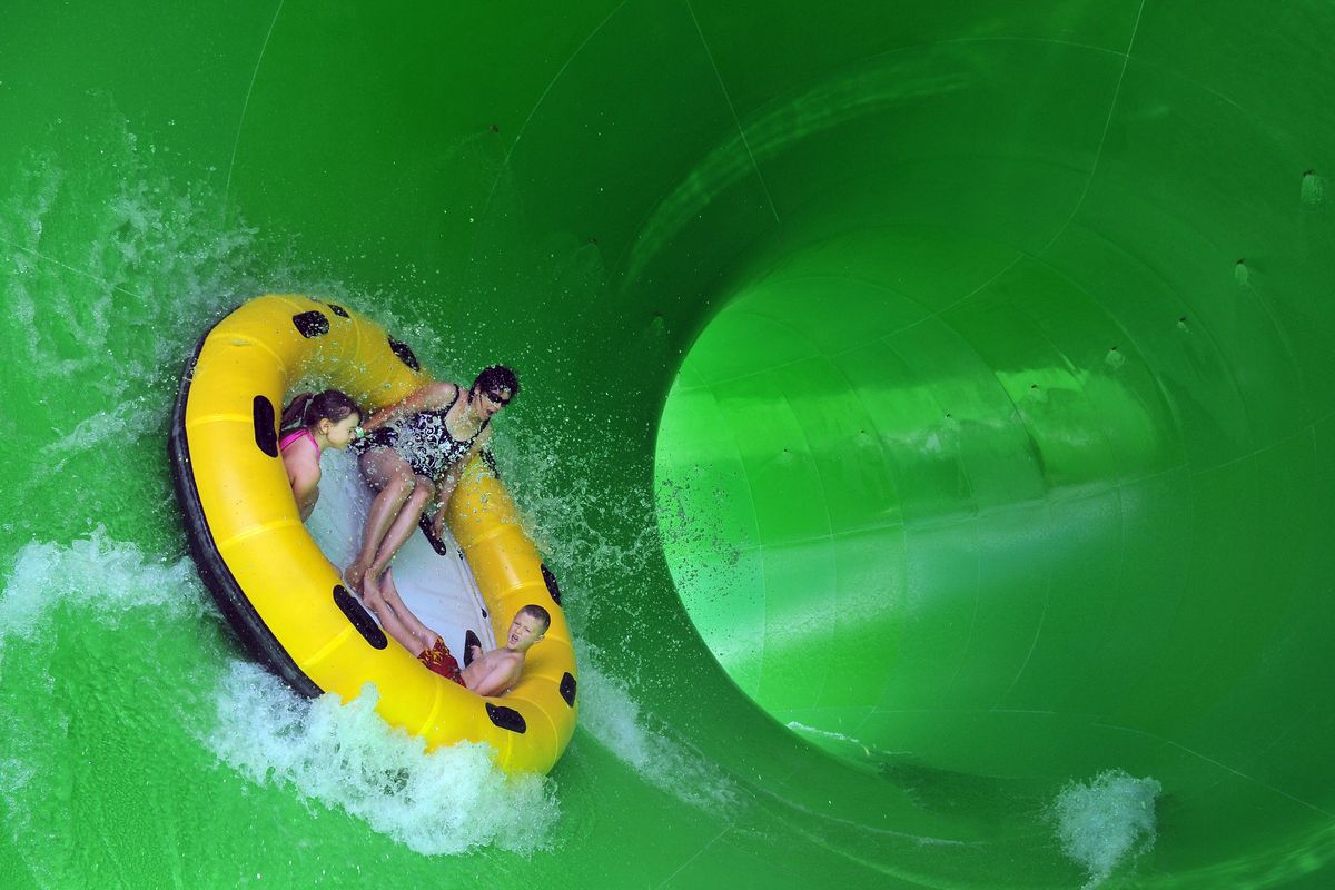 Laurel Pettey, center, and her children Alison, 8, left, and Jayden, 6, right, rocket up the side of a large tube on the new Ricochet Rapids waterslide Friday, July 15, 2011 at Silverwood Theme Park.  The new ride, which is adjacent to, and shares rafts with, the Avalanche Mountain slide, dumps rafts into a large tube where riders are tossed to and fro before dropping into a long dark tunnel for the rest of the ride down. (Jesse Tinsley / The Spokesman-Review)