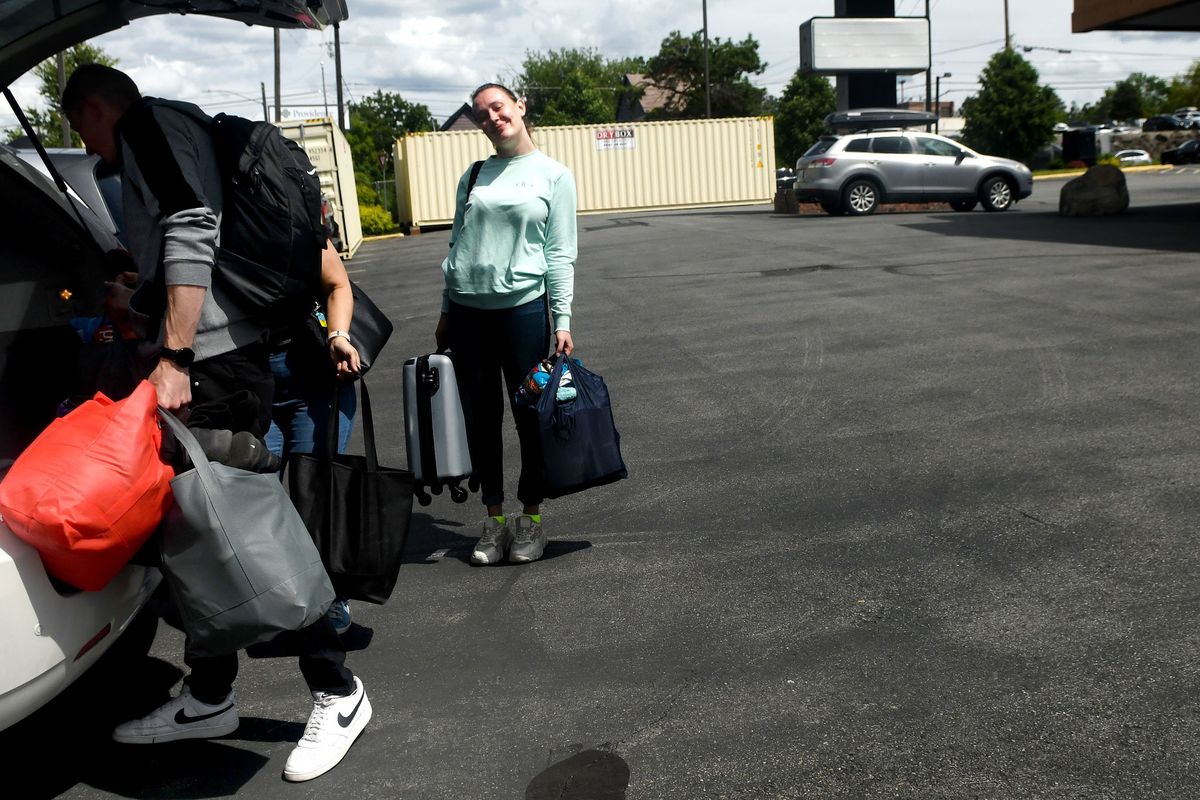 Ukrainian refugees Kazina Onyshko, center and Oleh Antonov, left carry their luggage into the former Quality Inn as part of Thrive International