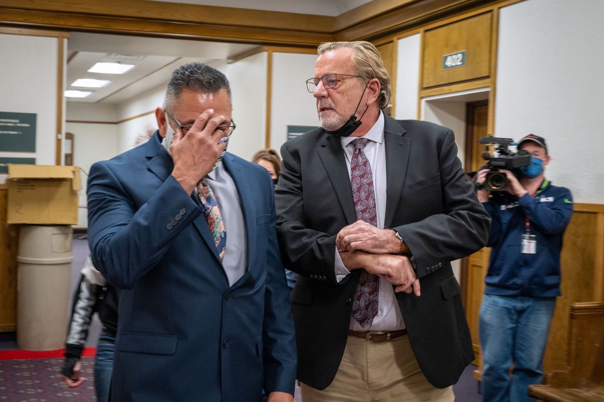 Former Pasco police officer Richard Aguirre hides his face as he leaves Spokane County Superior Court with lawyer John Browne on Thursday. The jury in Aguirre’s first-degree murder case was unable to come to a verdict, triggering a mistrial.  (COLIN MULVANY/THE SPOKESMAN-REVIEW)