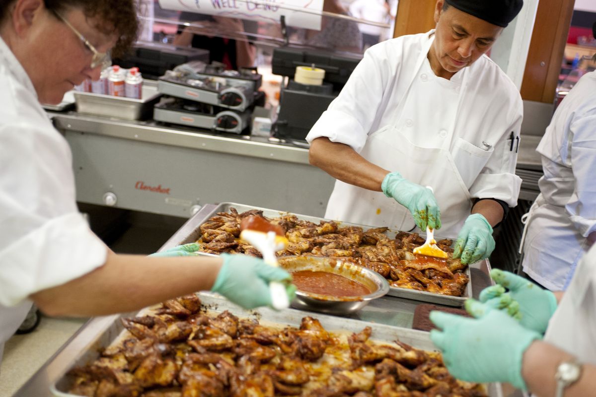 Nora Wynecoop, center, of the Wellpinit school district, prepares chicken during a Cook for America culinary boot camp Thursday at Cheney High School. The boot camp included local districts that have decided to prepare meals cooked from scratch. (Tyler Tjomsland)