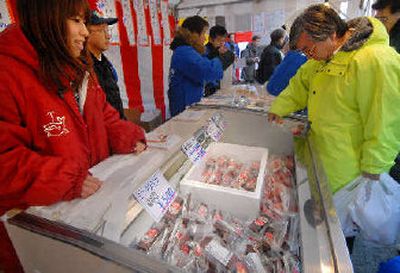 
A sales assistant clad in a coat with a blowing whale illustration attends a counter selling minke whale red meat, bacon and others at a special yearend fish market opened by fishermen's cooperative in Tokyo.  
 (Associated Press / The Spokesman-Review)
