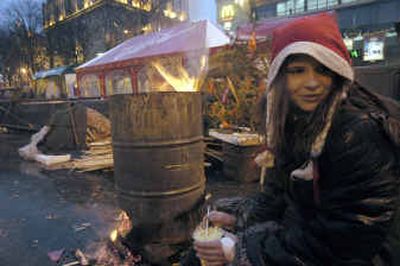 
A young resident of the tent camp, in Christmas hat, has a snack Friday on the main Kiev square, Ukraine.
 (Associated Press / The Spokesman-Review)