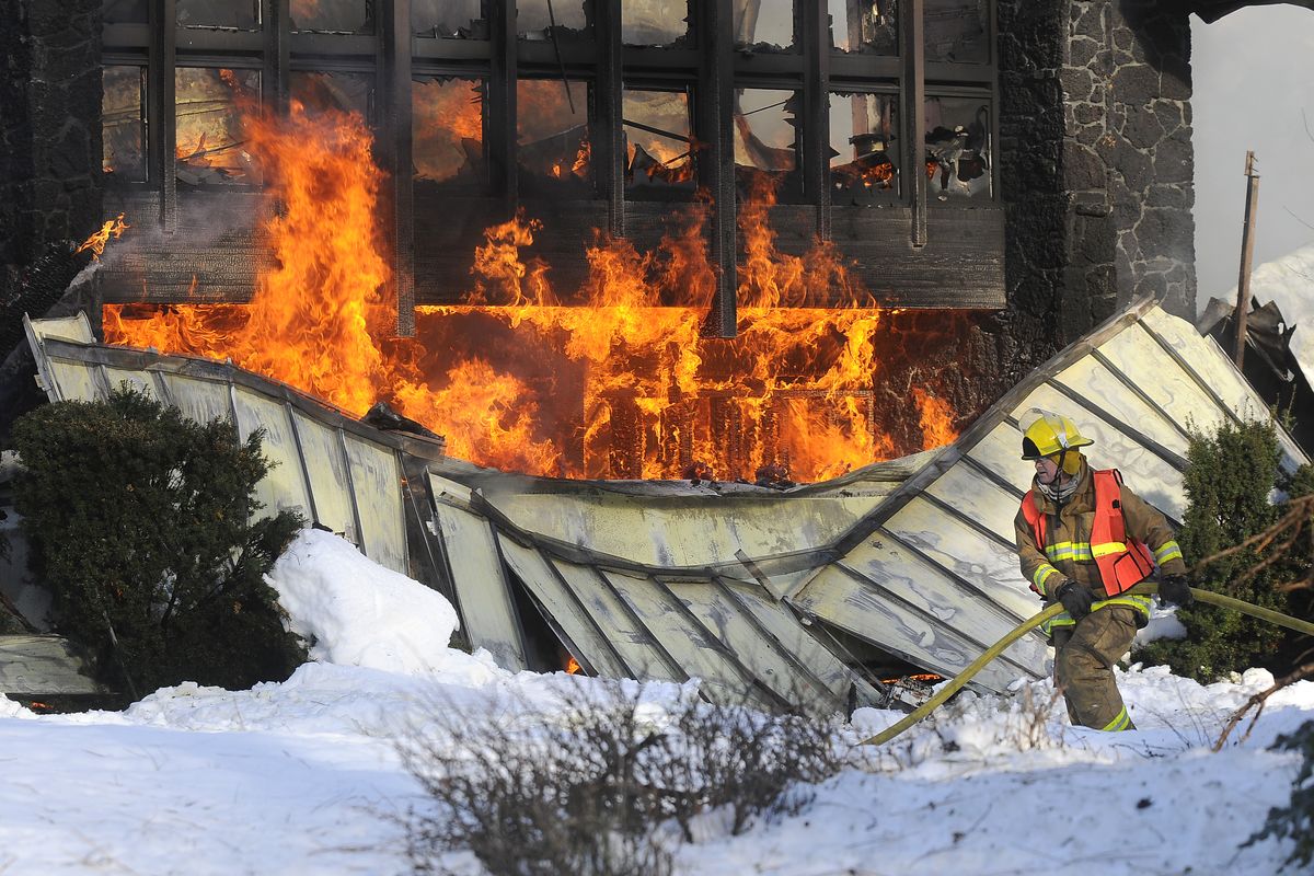 Spokane County Fire District #3 firefighter Barry Roach pulls hose past the collapsed roof as crews fight to contain a blaze at the main entrance of Seventh-day Adventist headquarters from spreading to the administrative offices Sunday, Dec. 28, 2008, at 3715 S. Grove near Spokane. (Dan Pelle / The Spokesman-Review)