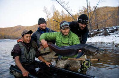 
Justin Crump draws a crowd of local guides and film crew members as he releases a taimen, which is nearly 50 inches long, during the filming of 