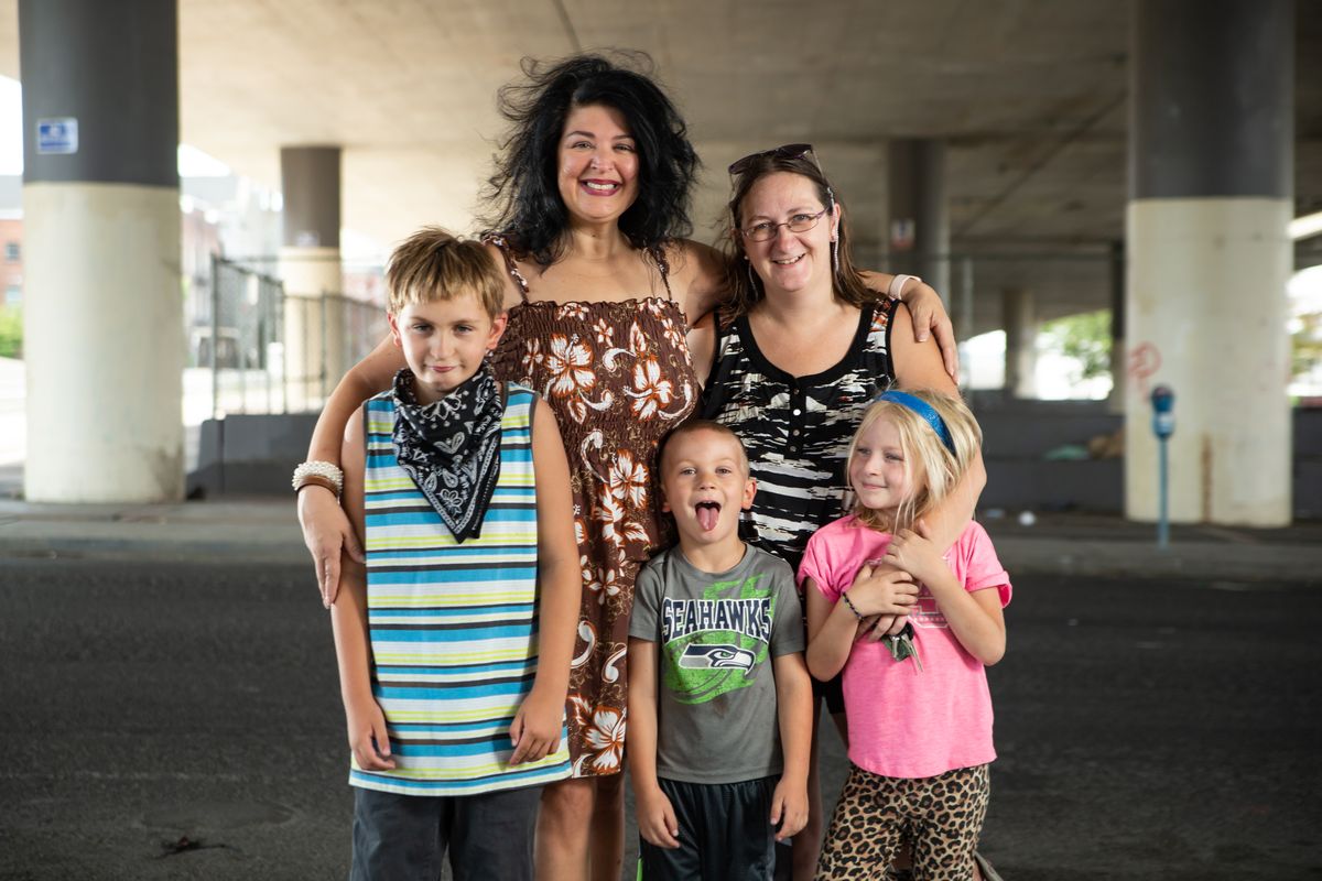 Jessica Kovac, clockwise from upper left, Becca Wells, 7-year-old Opheliah Rich, 5-year-old Avery Watson and 9-year-old Orion Rich are photographed at the location of Blessings Under the Bridge at McClelland and Fourth Avenue on Aug. 16. Kovac founded Blessings Under the Bridge 15 years ago and recently passed on the car, a 2001 Isuzu Rodeo, used to start it to Wells, who is a single mom.  (Libby Kamrowski/The Spokesman-Review)