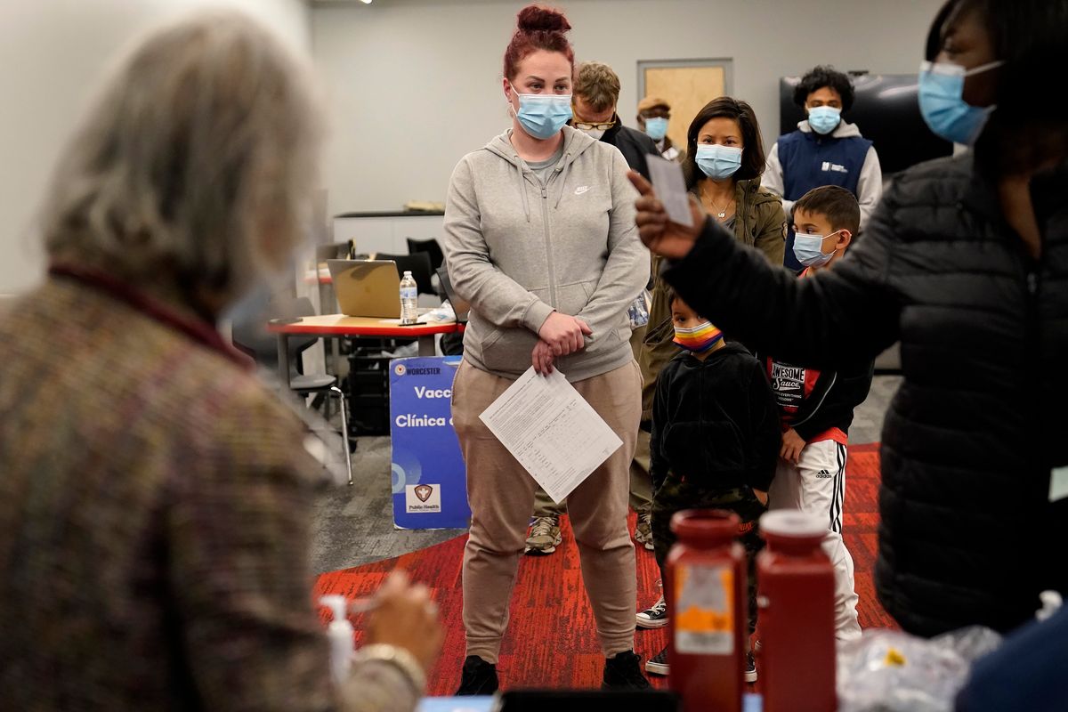 Leah Perkins, of Worcester, Mass., center, stands in line Thursday to receive a booster shot of the Pfizer COVID-19 vaccine at a mobile vaccination clinic, in Worcester. (Steven Senne)
