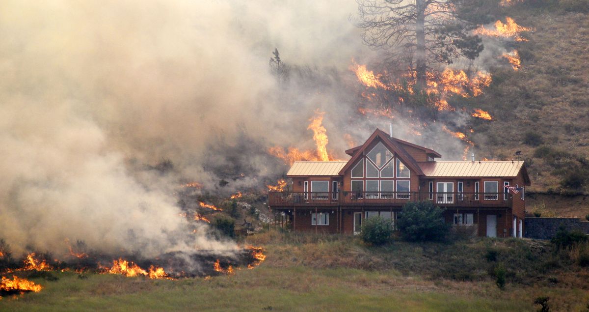Flames surround a house Tuesday, Aug. 14, 2012, on a hillside above Bettas Road near Cle Elum, Wash. Wildland firefighters on-site advised that the house survived the fire. The fast-moving wildfire has burned 60 homes across nearly 40 square miles of central Washington grassland, timber and sagebrush. No injuries have been reported but more than 400 people have been forced to flee. (Elaine Thompson / Associated Press)
