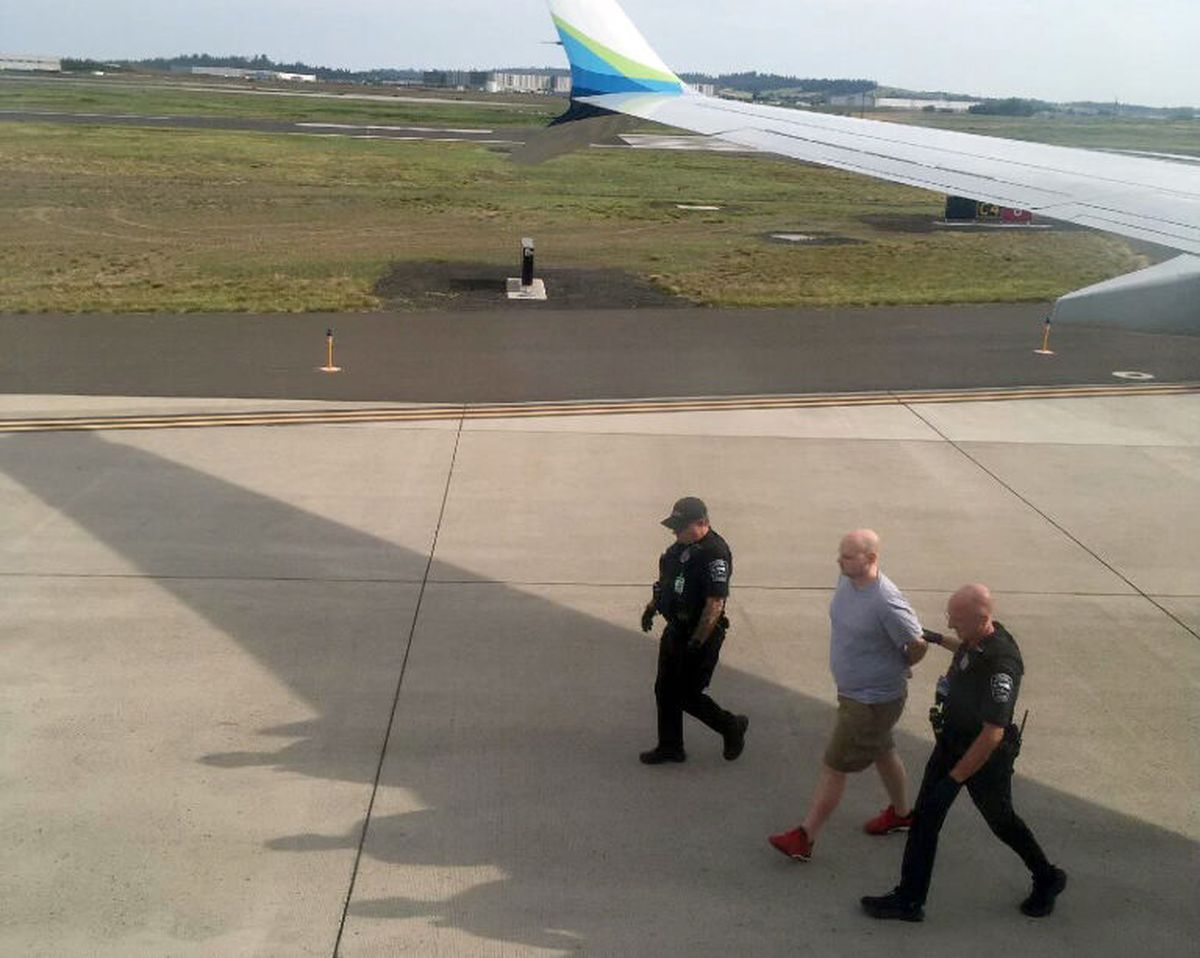Alaska Airlines passenger Brandon L. Scott is led away by authorities after his arrest Wednesday at Spokane International Airport.  (Courtesy Scott Mackie)