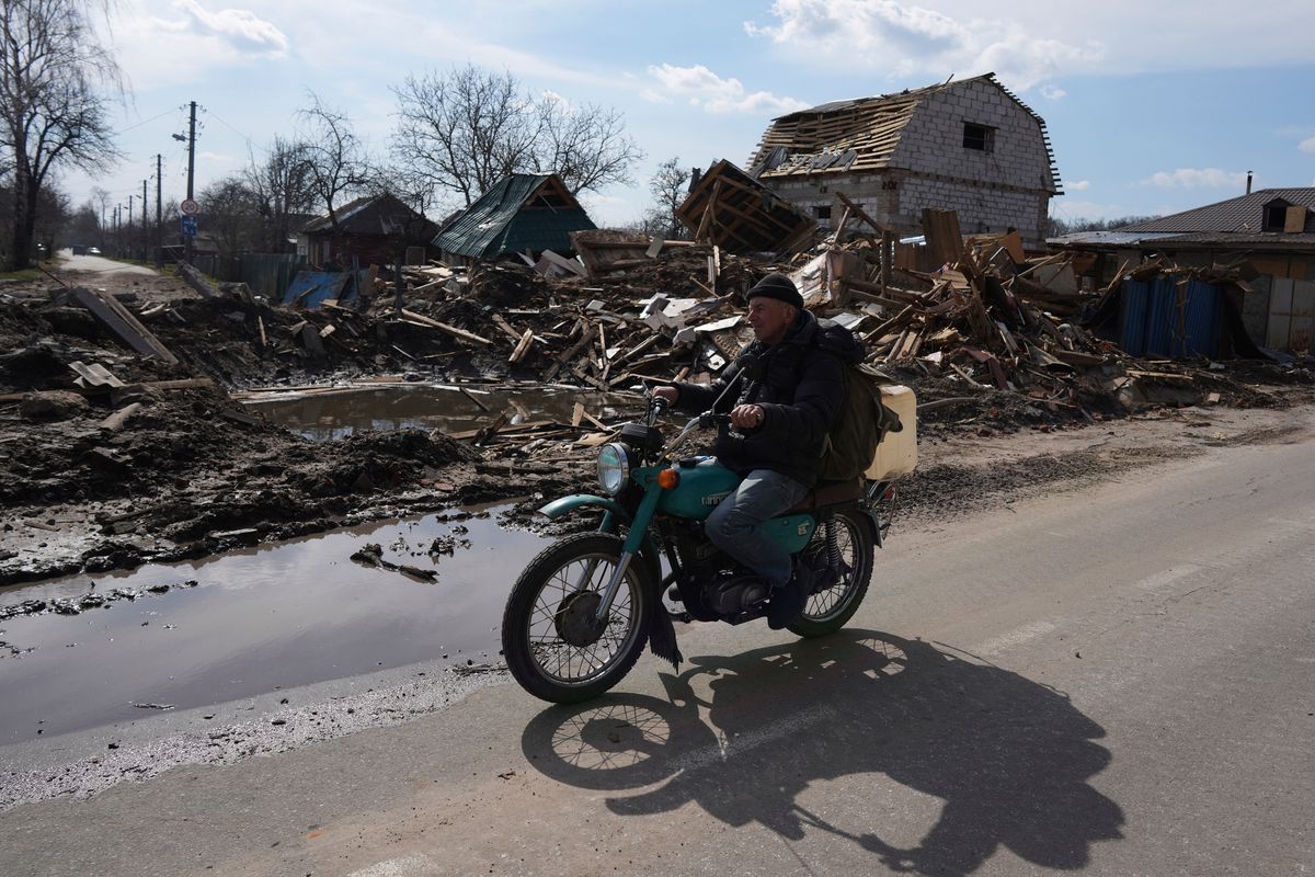 A man rides a motorbike on Thursday past a house damaged by shelling in Chernihiv, Ukraine.  (Evgeniy Maloletka)