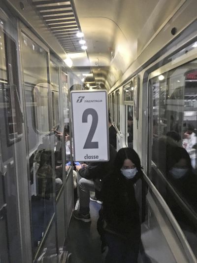 A woman wears a mask as people crowd a train from Padua, northern Italy, to Rome, early Sunday, March 8, 2020. Chaos and panic reigned as rumors spread that the Italian government was expanding its lockdown on Northern Italy to help contain the coronavirus, and many people tried to leave before being locked in one of the red areas. (Patricia Thomas / AP)