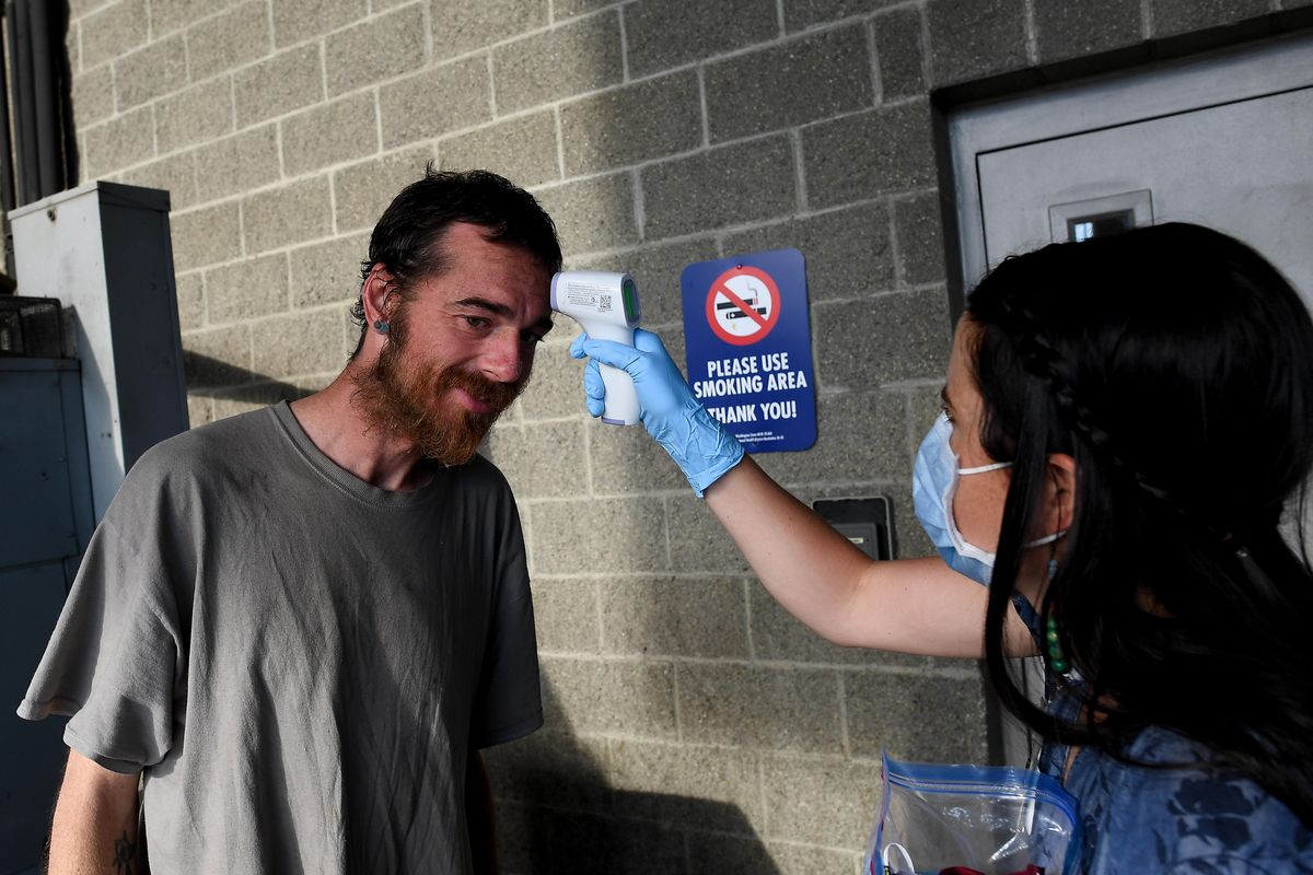 Kylie Kingsbury, right, Homeless Outreach Coordinator, with the Spokane Regional Health District checks the temperature of Stephen O