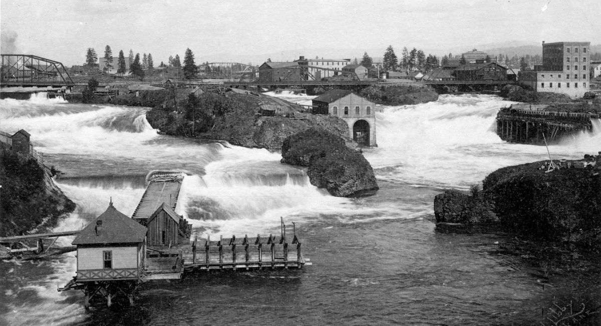 Circa 1888: The wooden structure at the lower left is an early Spokane water works, which likely featured water turbines to drive pumps to get the water up to street level. The small brick mill in the center, on the edge of what is now called Canada Island, is the Echo Roller Mill, one of several around the falls that produced flour from local grains using water-powered machinery. The 1888 Howard Street bridges, seen in the distance, were the first access across the river downtown, and the first Monroe Street bridge, made of wood, came a few years later. This photo predates the first hydroelectric dams, which began construction around 1890.
