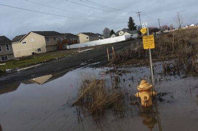 
The walking path along Strong Road at the entrance to the Falcon Ridge housing development on Five Mile Prairie is flooded after heavy rains and snow. 
 (Kathryn Stevens / The Spokesman-Review)