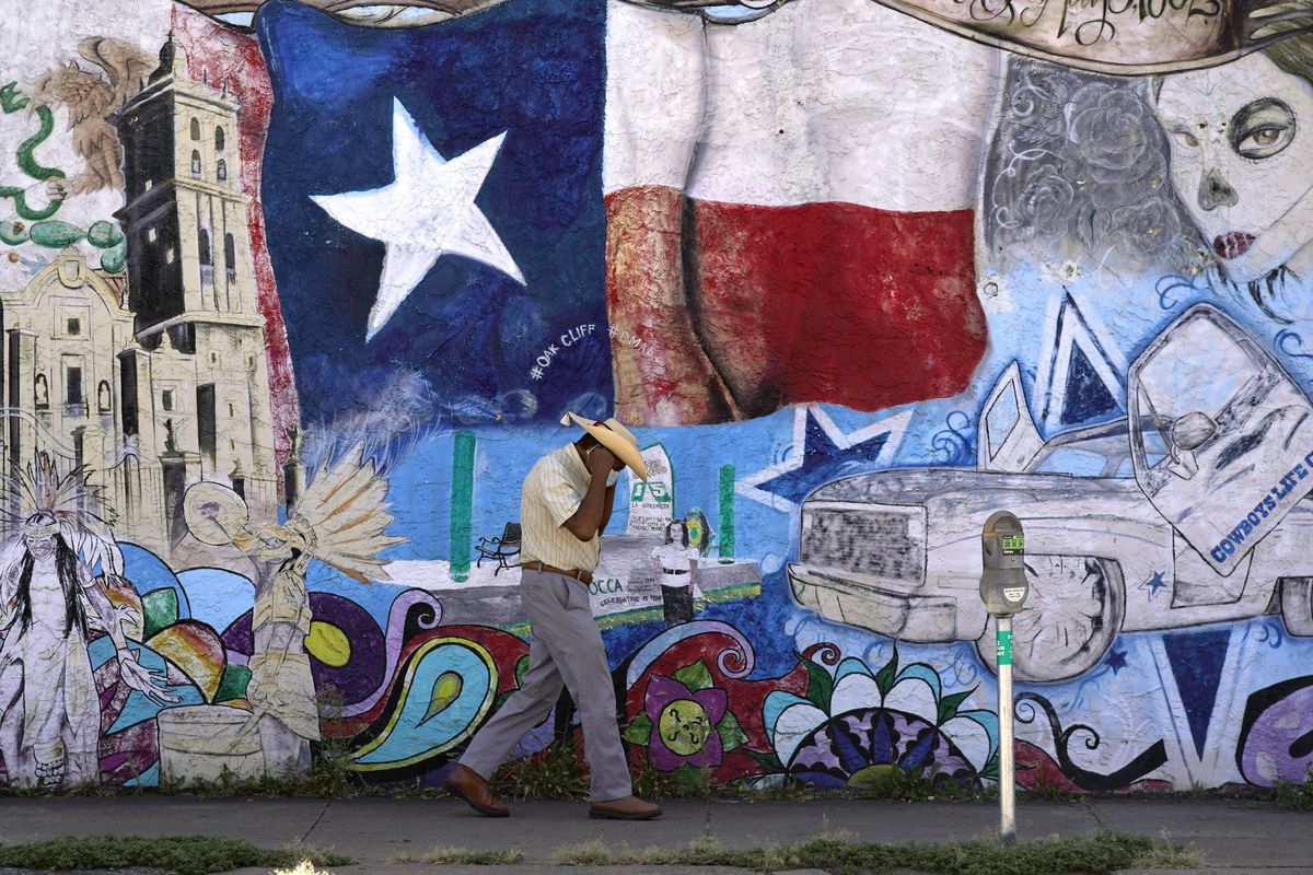 A man adjusts his face mask as he walks past a mural in the heavily Latino section of Oak Cliff in Dallas, Wednesday, Sept. 22, 2021. Texas this week will begin redrawing congressional lines, and Latino advocates and officeholders say it