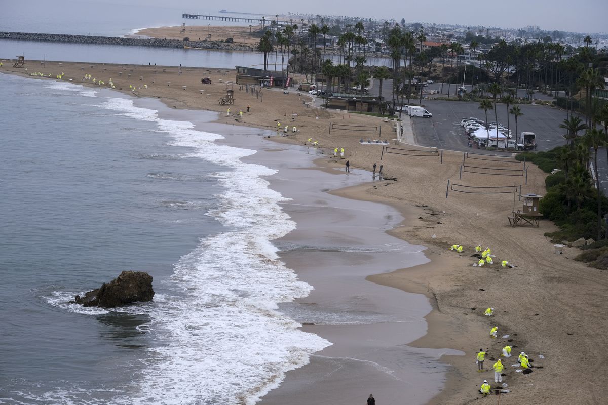 In this Thursday, Oct 7, 2021 photo, Workers in protective suits clean the contaminated beach in Corona Del Mar after an oil spill in Newport Beach, Calif. California