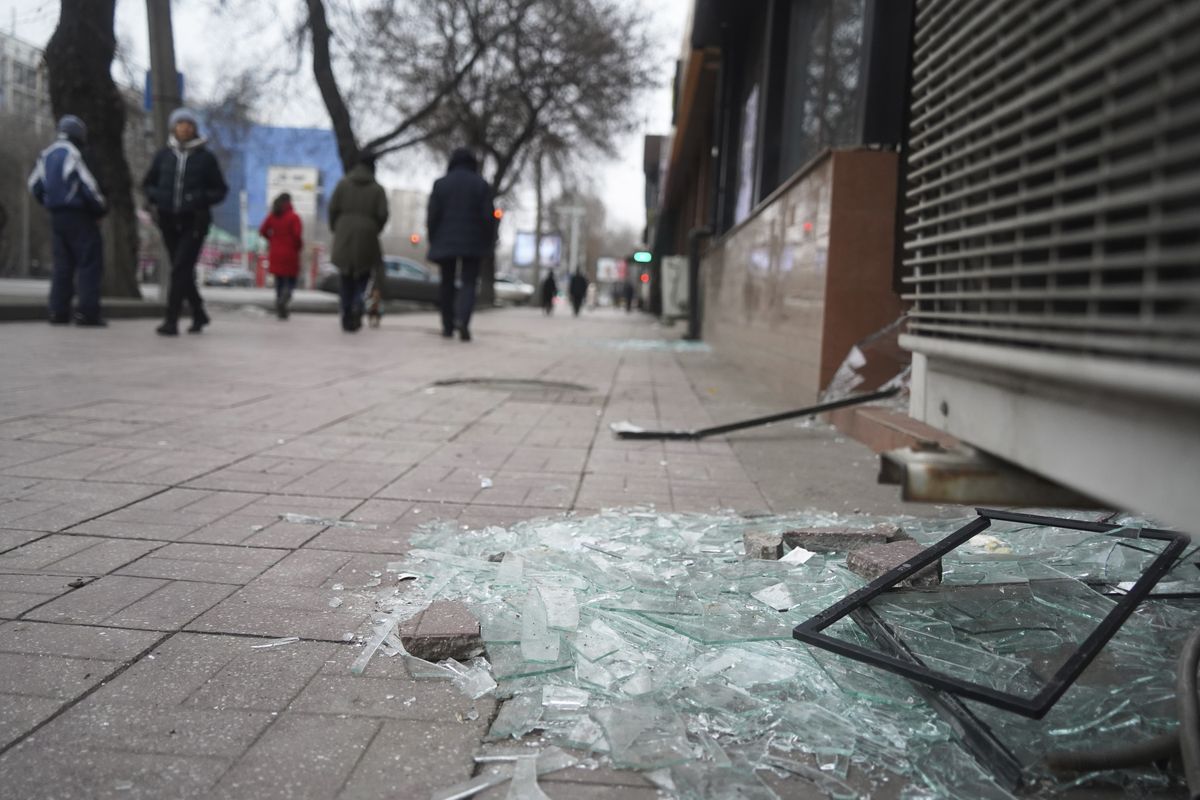 People walk past a shop with windows broken during clashes in Almaty, Kazakhstan, Monday, Jan. 10, 2022. Kazakhstan