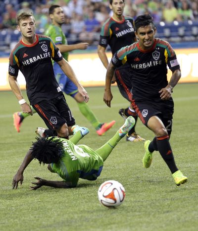 Galaxy's Robbie Rogers, left, and A.J. DeLaGarza pursue the ball after Sounders’ Obafemi Martins bites the turf Monday. (Associated Press)