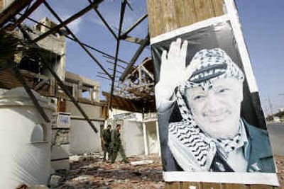 
Palestinian policemen walk by a poster of Yasser Arafat  on Sunday at Arafat's previously destroyed Gaza headquarters. 
 (Associated Press / The Spokesman-Review)