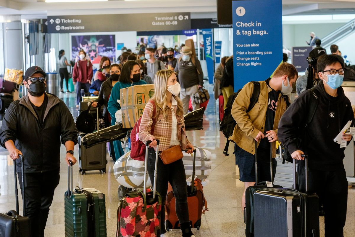 Holiday travelers wearing face masks line to check in Wednesday at the Los Angeles International Airport. (Ringo H.W. Chiu)